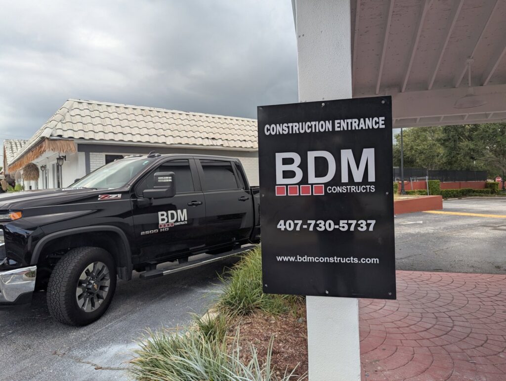 A BDM Construction, Inc truck parked near a 'Construction Entrance' sign in Orlando, FL