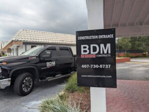 A BDM Construction, Inc truck parked near a 'Construction Entrance' sign in Orlando, FL