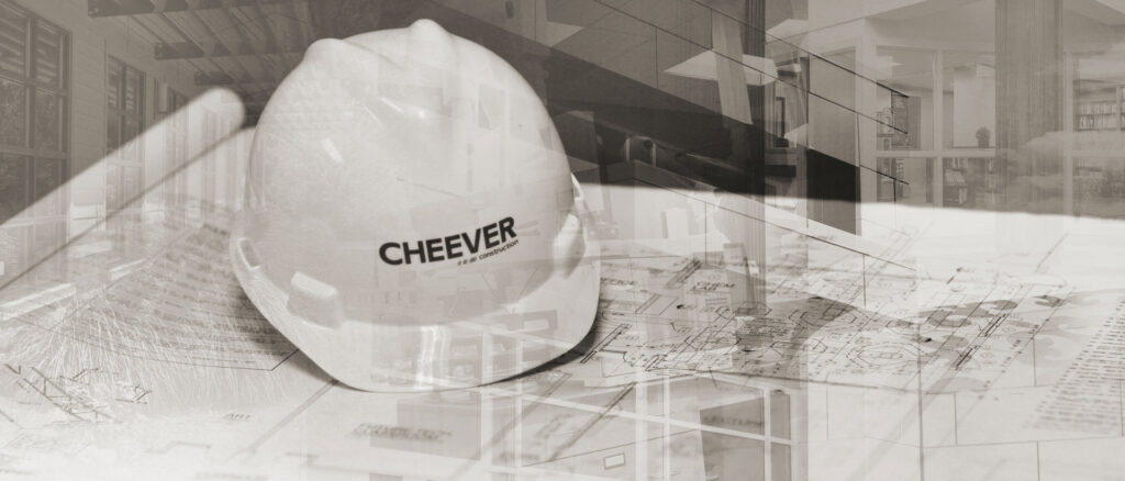 A white construction hard hat resting on blueprints, symbolizing planning for Cheever Builders in Grand Rapids, MI.