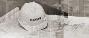 A white construction hard hat resting on blueprints, symbolizing planning for Cheever Builders in Grand Rapids, MI.