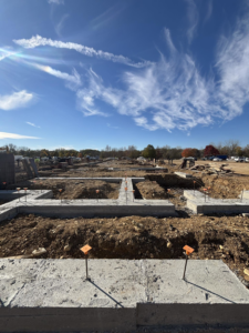 A construction site with newly poured concrete foundations and rebar under a blue sky by K.R. Miller Contractors in Chicago, IL.