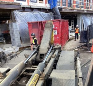 A Geppert Recycling truck placing a red dumpster at a construction site for debris removal in Philadelphia, PA.