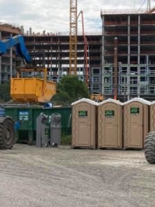 A green roll-off dumpster from Waste Services, LLC at a busy construction site in Charleston, SC.