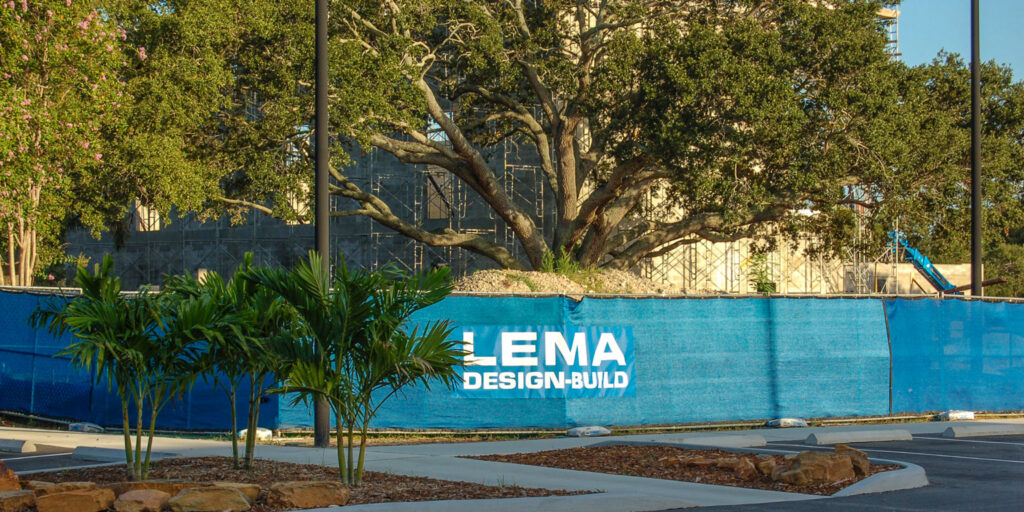 A construction site with LEMA Design-Build fencing, indicating a project by LEMA Construction, Inc. in Saint Petersburg, FL.