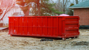 A large red roll-off dumpster on a construction site for debris removal services in West Fargo, ND.