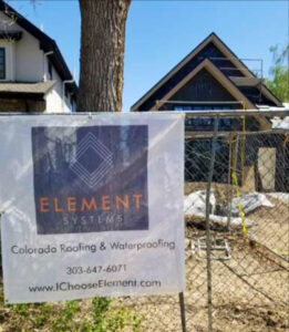 A construction site with a banner for Element Systems Colorado Roofing & Waterproofing in Wheat Ridge, CO