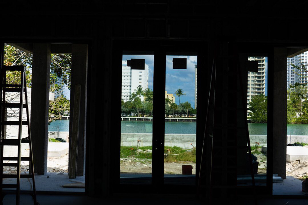 A view from inside a construction site, showing a waterfront property and distant buildings by Intelligent Construction Inc. in Miami, FL.