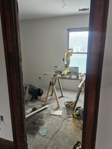 Construction tools including a miter saw and flooring planks in a room under renovation by Done Well Home Improvement LLC in Buffalo, NY.