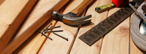 Various construction tools including a hammer, nails, tape measure, and wood planks, representing NH Handyman services in San Diego, CA.