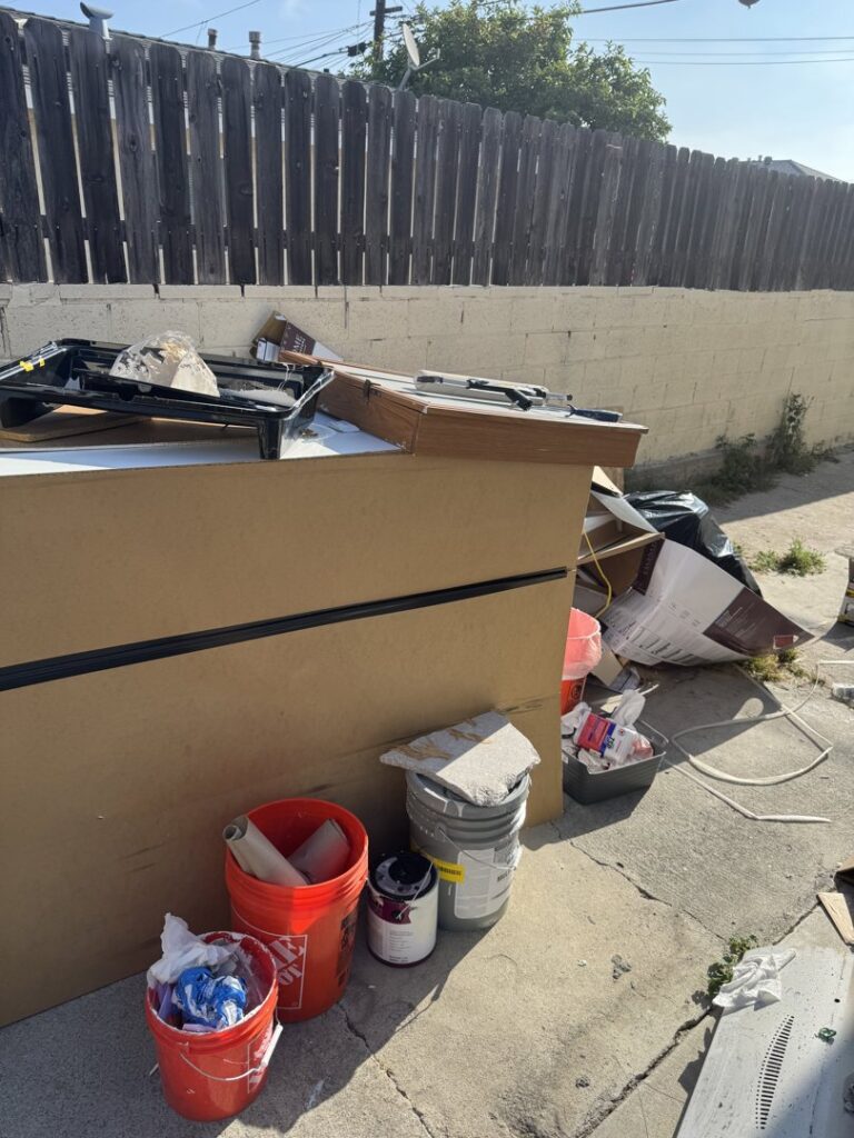 A large pile of construction waste, cardboard, and paint buckets for removal by Elite Hauling & Junk Removal in San Diego, CA.