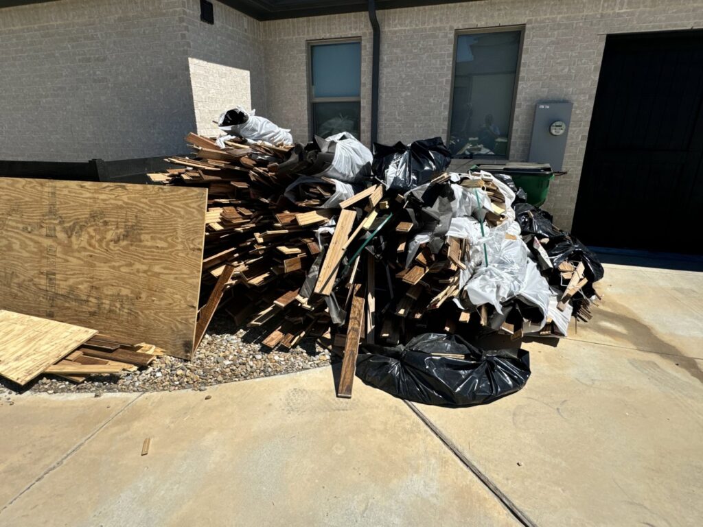 A large pile of construction wood debris and trash bags ready for removal by JB'S Junk Removal in Justin, TX.