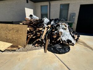 A large pile of construction wood debris and trash bags ready for removal by JB'S Junk Removal in Justin, TX.