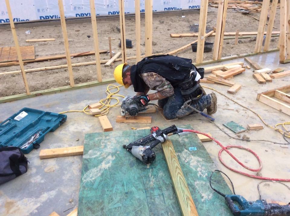 A construction worker cutting wood for framing on a concrete slab, demonstrating work by Texas Wounded Veterans Builders and Contractors in McKinney, TX.