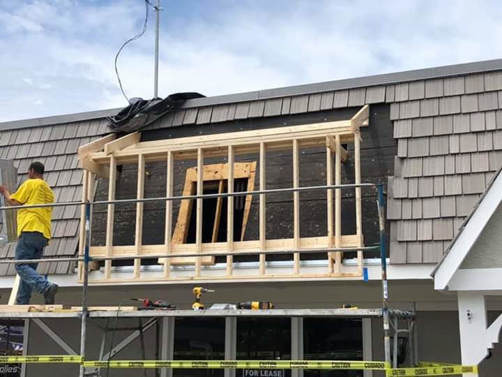 A construction worker on scaffolding framing a dormer window on a roof for Unique Construction Services in Knoxville, TN