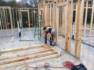 A construction worker framing the interior walls of a new home on a concrete slab, demonstrating work by Texas Wounded Veterans Builders and Contractors in McKinney, TX.