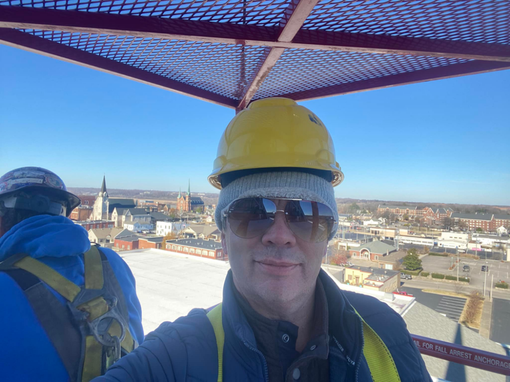 A construction worker in a hard hat and safety harness on a roof at Azure Construction in Clarksville, TN