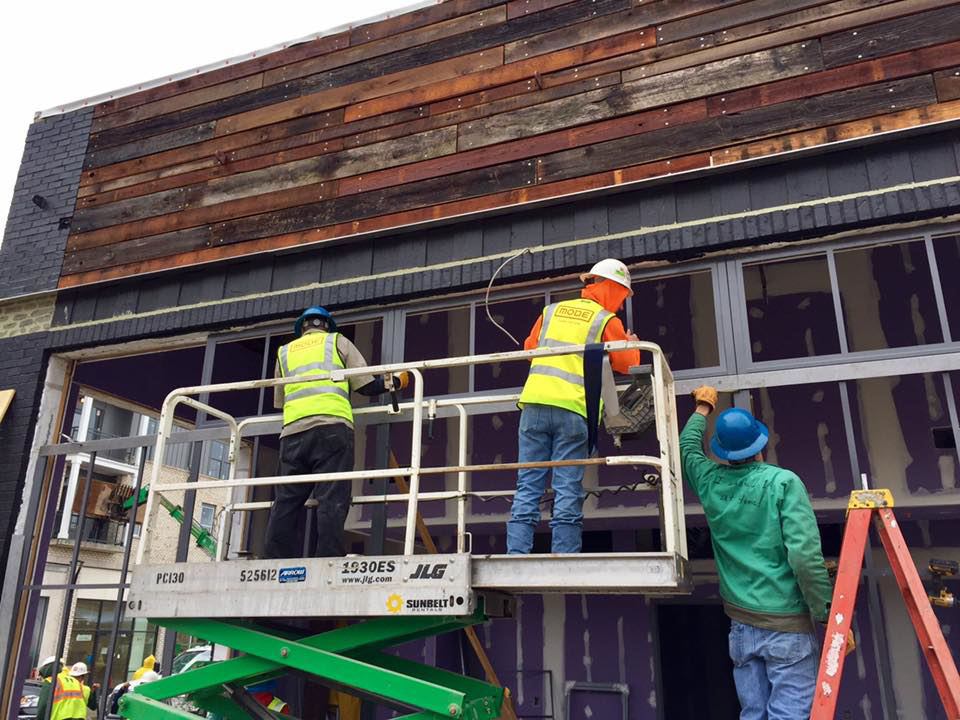 Construction workers on a scissor lift installing exterior siding and windows for Recreated in Birmingham, AL.
