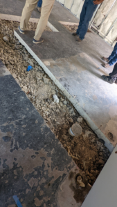 Construction workers on site overseeing concrete floor and plumbing work by Rivera Services in Chandler, TX.