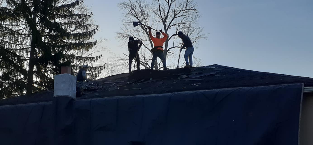 Construction workers tearing off an old roof during a renovation project by Manny's Sb Construction Inc in Goshen, NY.