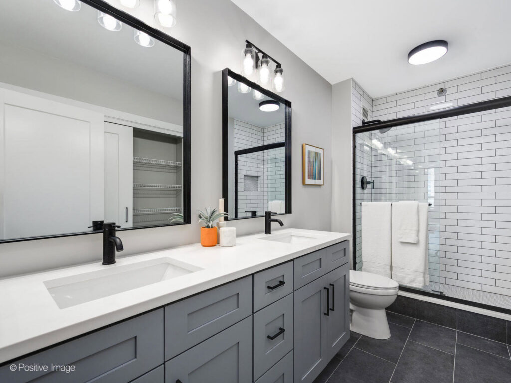 A contemporary bathroom remodel featuring a double vanity and subway tile shower by Inland Home Remodeling Inc. in Chicago, IL.