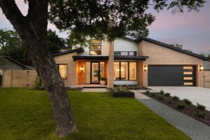 A contemporary brick and white facade home featuring a modern garage door and landscaping by Stone Acorn Builders in Bellaire, TX.
