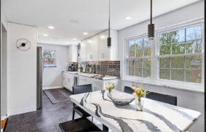 A contemporary kitchen design featuring white cabinets and a unique marble-patterned island by Integrated Contracting and Renovations in Pittsburgh, PA.