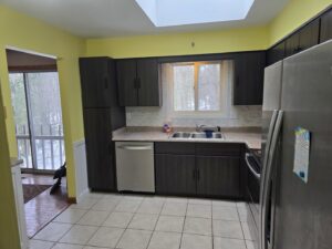 A contemporary kitchen remodel featuring dark wood cabinets, light countertops, and a tiled backsplash by Ben Nye The Fix-It Guy in Erie, PA.