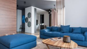 A contemporary living room with a large blue sofa, showcasing interior design by Coastal Pointe Homes in Tampa, FL.