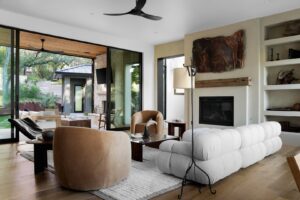 A contemporary living room featuring a fireplace, built-in shelving, and large sliding doors to the outside by Stone Acorn Builders in Bellaire, TX.