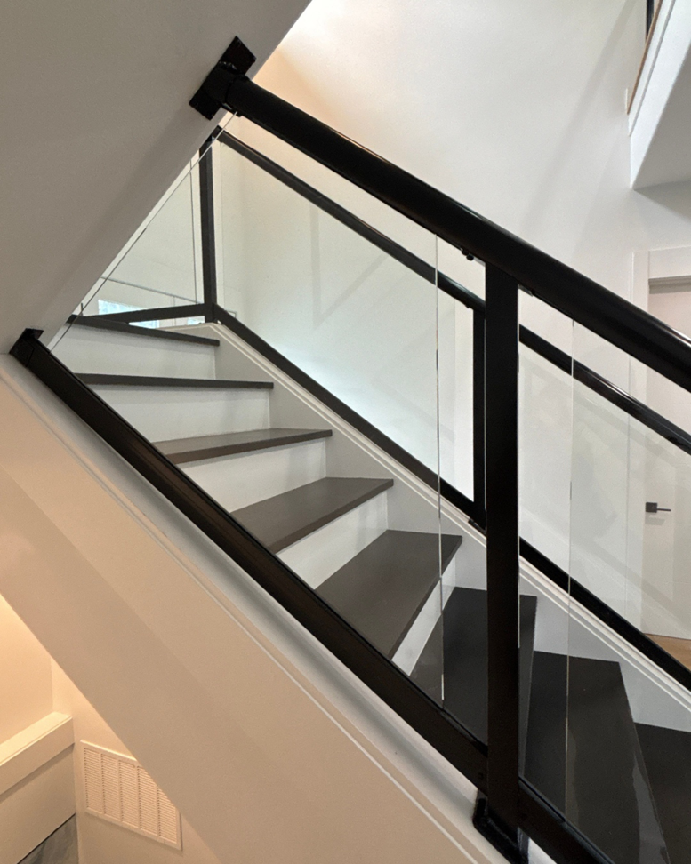 A contemporary staircase featuring elegant black framed glass railings installed by Alpha Railing Company in Tacoma, WA.