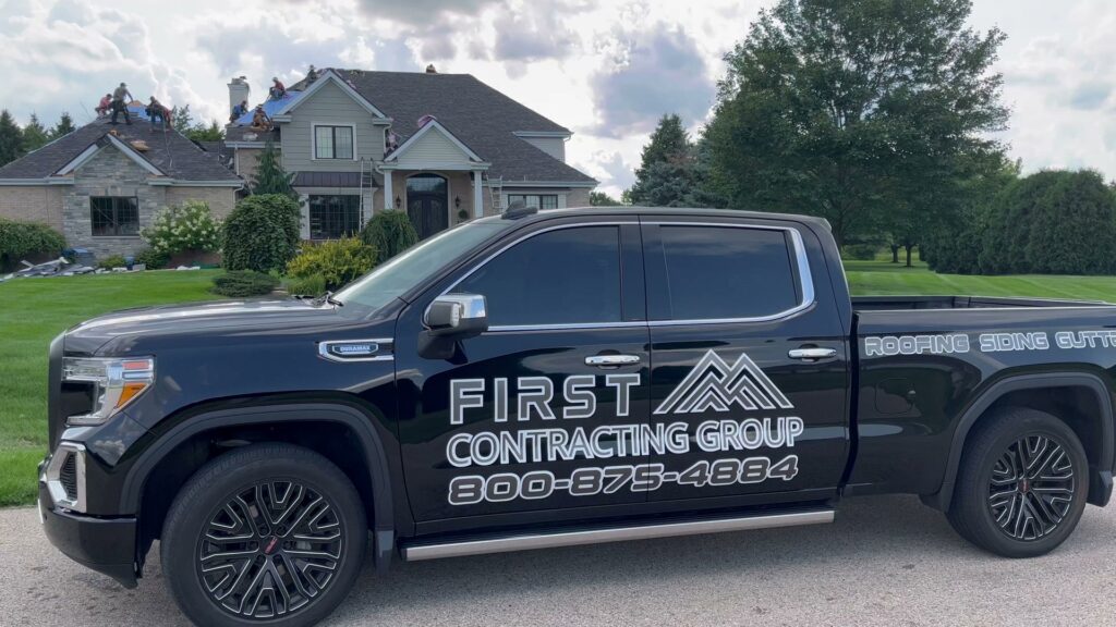 A First Contracting Group truck parked in front of a home with new siding and roofing in Rockford, IL.