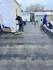Contractors cleaning a flat roof before applying a new coating by DunnWright Contractor in Pensacola, FL.