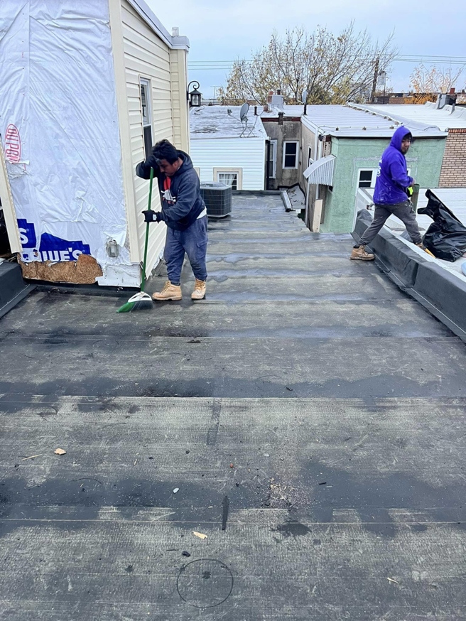Contractors cleaning a flat roof before applying a new coating by DunnWright Contractor in Pensacola, FL.
