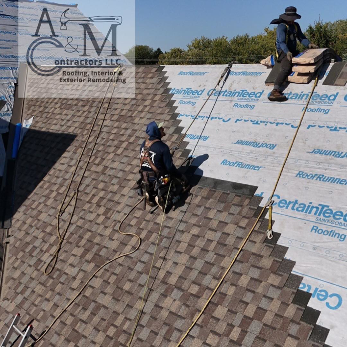 Contractors installing new roof shingles on a residential property for A&M Contractors LLC in Waukesha, WI