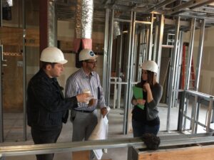 General contractors and clients reviewing blueprints on a commercial construction site with exposed framing and ductwork by Siegel Construction in Eugene, OR.