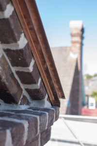 Close-up of copper flashing and brickwork on a building, showcasing quality exterior repair by Meadors, Inc in North Charleston, SC.