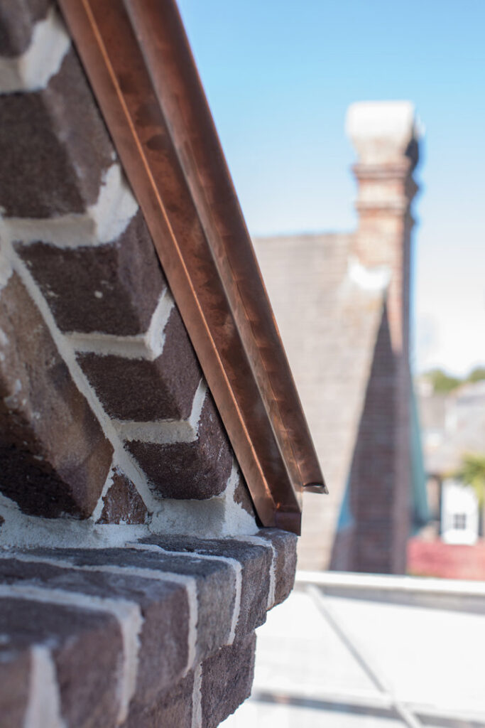 Close-up of copper flashing and brickwork on a building, showcasing quality exterior repair by Meadors, Inc in North Charleston, SC.