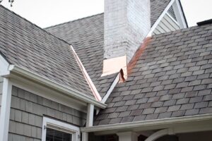 New copper flashing installed around a chimney on a roof, a handyman service by Consolidated Roofing Systems, Inc. in Cary, NC