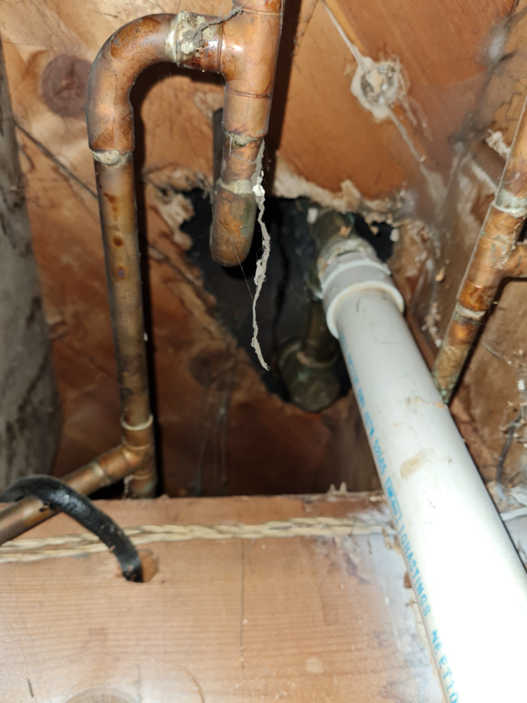 Close-up of copper and PVC plumbing pipes in a wall cavity, showing repair or installation work by All American Handyman services in Billings, MT