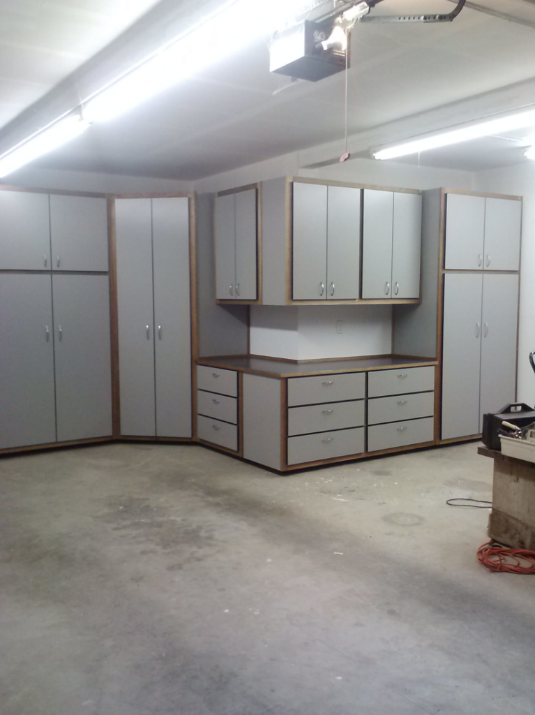 A corner installation of grey garage cabinets with a workbench and drawers by NW Garage Cabinet Company in Ridgefield, WA.