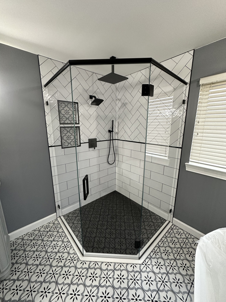 A stylish corner shower enclosure with white subway tiles and a black-framed glass door by Fortune Shower Doors in Sterling Heights, MI.