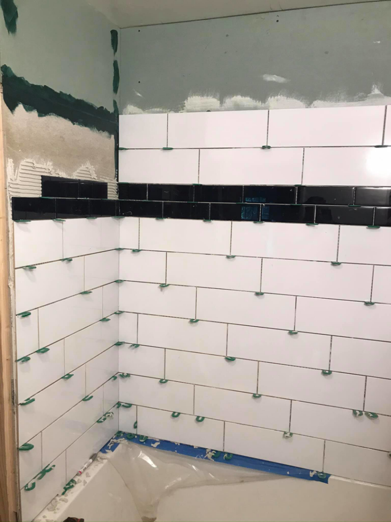 Corner of a bathroom shower area with white and black subway tiles being installed by Ken Sweeney Property Solutions in Knoxville, TN