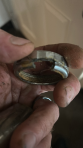 A hand holding a corroded metal pipe fitting, showing a plumbing replacement service by Katzenstein llc handyman in Council Bluffs, IA.