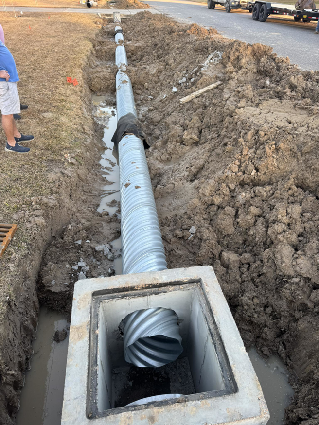 Corrugated drainage pipe installation leading into a concrete catch basin by Rolloff Rentals / Rolloff Services in Port Angeles, WA.