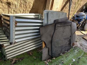 Corrugated metal sheets and old car mats piled up for junk removal by Impact Environmental Co. in El Cajon, CA.