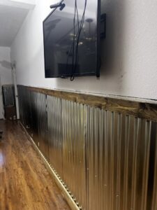Corrugated metal wall paneling installation with mounted TV by Iron Horse Handyman Services LLC in Laramie, WY.