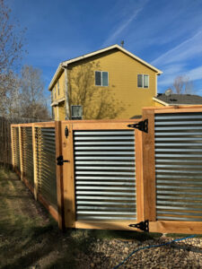 A corrugated metal and wood fence with a gate installed by GreenView Solutions in Denver, CO.