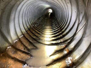 An interior view of a corrugated pipe with water and debris, inspected by Precision Industrial Maintenance, Inc. in Schenectady, NY.