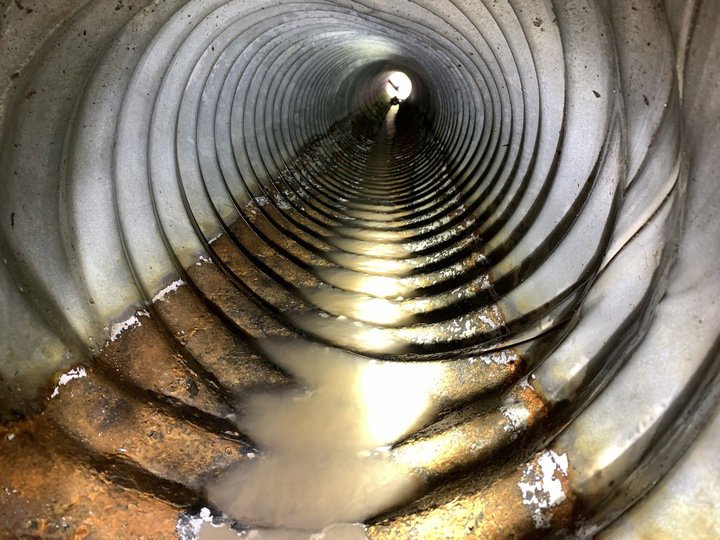 An interior view of a corrugated pipe with water and debris, inspected by Precision Industrial Maintenance, Inc. in Schenectady, NY.