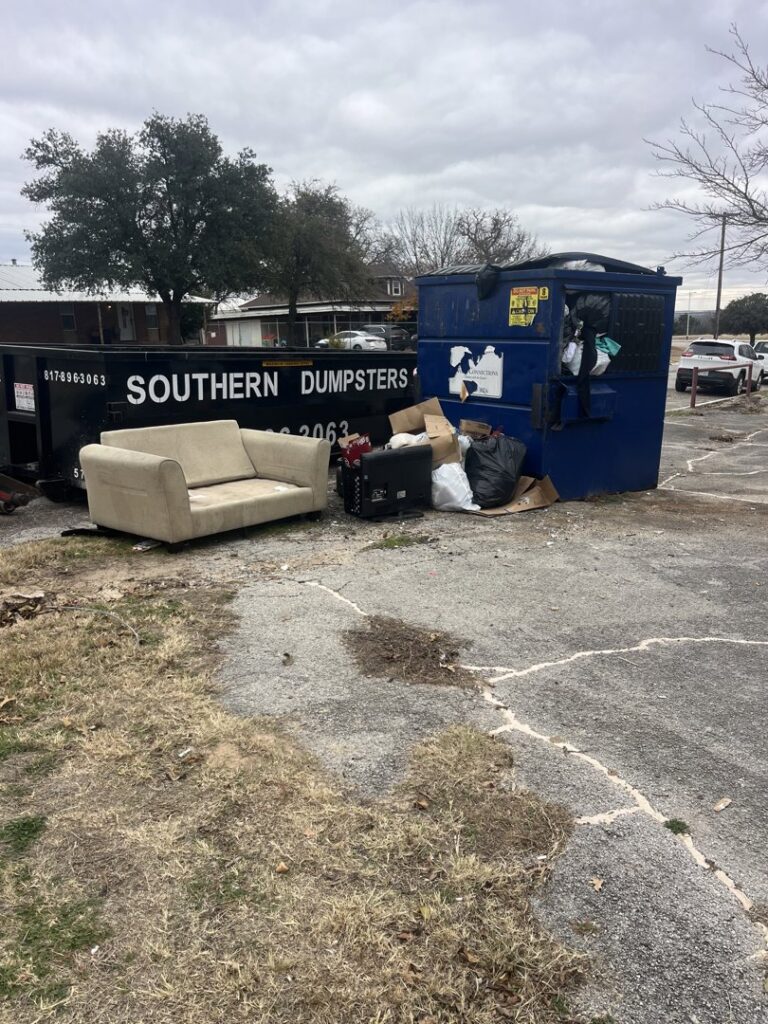 A discarded couch and various debris placed next to a dumpster for removal by NTX Haul Away Junk Removal in Fort Worth, TX.